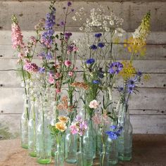 a group of vases filled with flowers on top of a wooden table