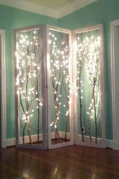 two doors decorated with lights and trees in the middle of a wooden floored room