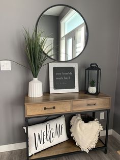 a wooden table topped with a mirror next to a plant and a sign that says welcome