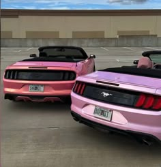 two pink mustangs are parked in a parking lot