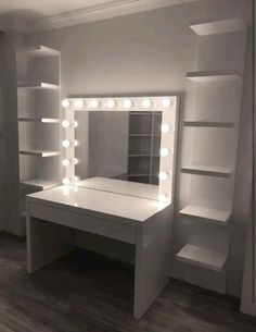 a white vanity with lights on it and shelving unit in the corner behind it