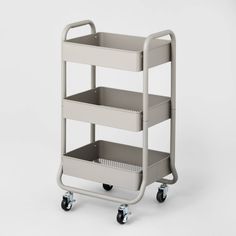 a three tiered plastic utility cart with wheels on the front and bottom, in light grey