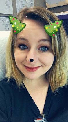 a woman with blue eyes and a fake nose has green decorations on her ears as she smiles at the camera