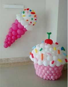 two ice cream cones with sprinkles and balloons on the wall next to each other