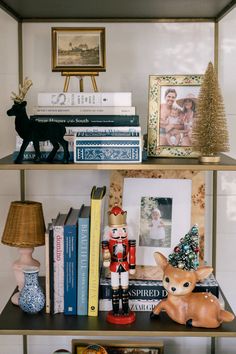 a shelf filled with books and figurines on top of it next to a lamp