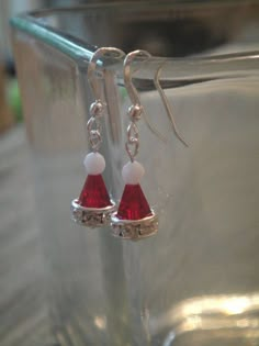 a pair of red and white earrings sitting on top of a glass container next to a cup