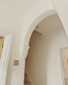 an arched doorway leading to a hallway in a house with white walls and wood floors