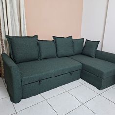 a green couch sitting on top of a white tiled floor