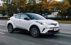 a white toyota c - hr driving down the road