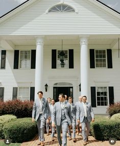 a group of men standing in front of a white house