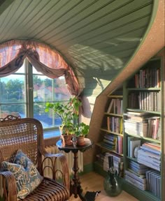 a living room filled with furniture next to a window covered in curtains and bookshelves