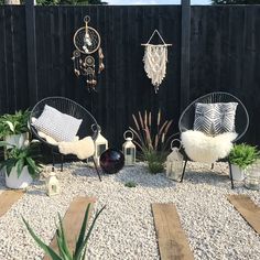 two black chairs sitting on top of a gravel covered ground next to a wooden fence