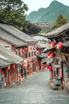 an alley way with lots of buildings and lanterns hanging from the side of each building