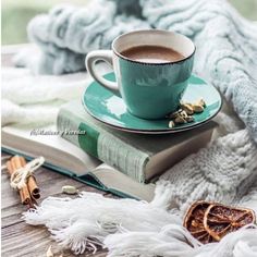 a cup of coffee sitting on top of a green saucer next to an open book