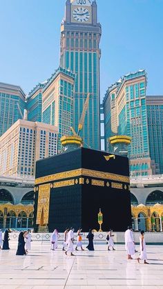 the ka'bah in front of some tall buildings with a clock on it