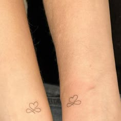 two people with matching tattoos on their arms, one has a heart and the other has a cross