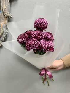 a person holding a bouquet of purple flowers