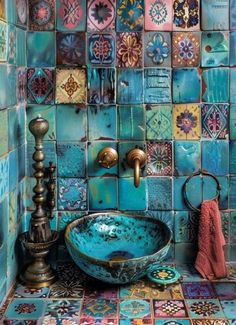 a blue sink in a bathroom with colorful tiles on the wall behind it and a red towel next to it