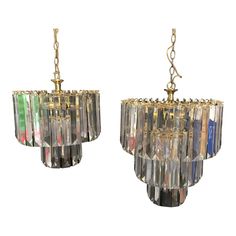 two chandeliers hanging from chains, one with multicolored glass and the other gold