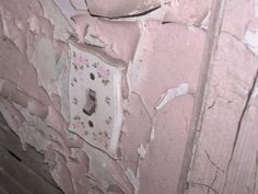 an old light switch on the side of a pink wall with peeling paint and flowers