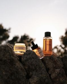 two bottles of skin care sitting on top of some rocks