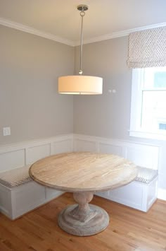 a table and bench in a room with wood flooring, white walls and wooden floors