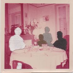 two people sitting at a table in front of a vase with flowers and plates on it