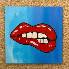 a painting of a red lips with white teeth on a blue background is featured in the foreground