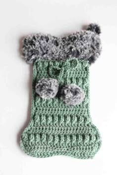 a green crocheted stocking with pom poms