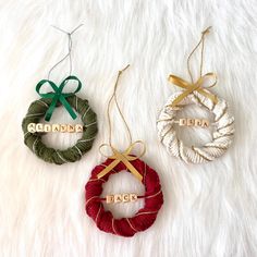 three christmas wreaths with names hanging from them on a white furnishing surface