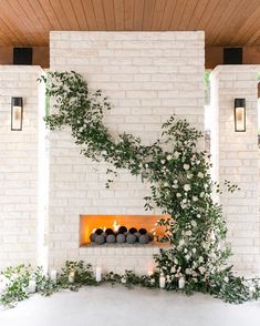 an indoor fireplace with candles and greenery on the mantle, surrounded by white brick walls