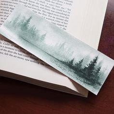 an open book with trees on it sitting on top of a table next to a knife