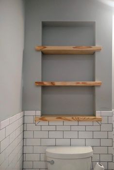 a white toilet sitting in a bathroom next to a shelf filled with wooden planks