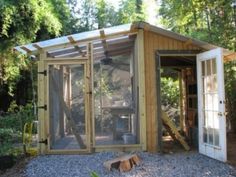 a chicken coop built into the side of a wooded area with an open door and windows