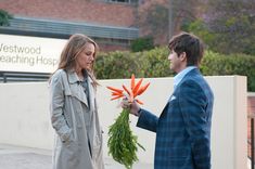 a man and woman standing next to each other in front of a sign that says you said no flowers