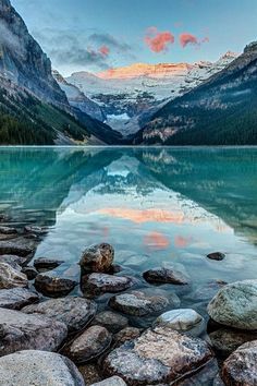 a lake surrounded by mountains with rocks in the foreground