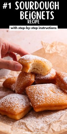 a pile of powdered sugar doughnuts sitting on top of a wooden cutting board