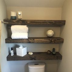 a bathroom with three shelves above the toilet and two towels on top of each shelf