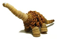 a stuffed animal made out of pine cones on a white surface with one leg up