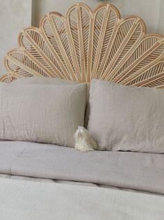 a close up of a bed with pillows and a headboard made out of wicker