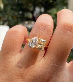 a person's hand with a yellow and white diamond ring on top of it