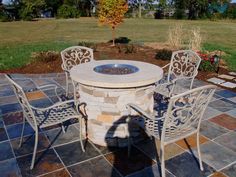 an outdoor table with chairs around it and a fire pit in the middle of the yard