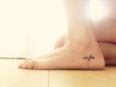 a woman's foot with the word run free tattooed on her left side leg