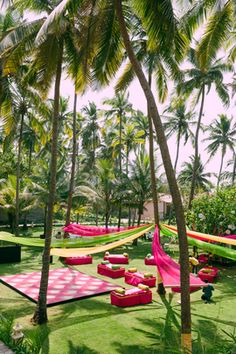 the lawn is decorated with pink and white checkered rugs, hammocks, and trees