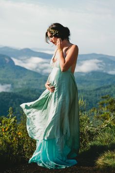 a pregnant woman standing on top of a mountain