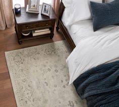 a bed sitting next to a wooden dresser on top of a hard wood floor covered in pillows