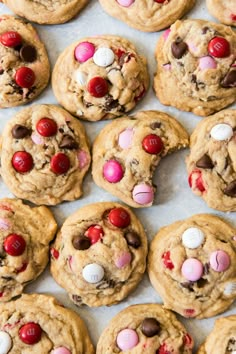 chocolate chip cookies with m & m's and candy eyes on top, lined up in rows