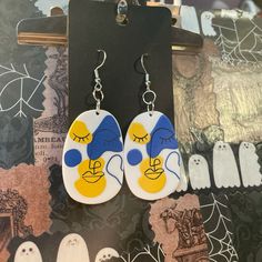 a pair of earrings with ghost faces painted on them