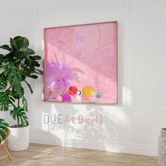 a painting hanging on the wall next to a potted plant in a white room