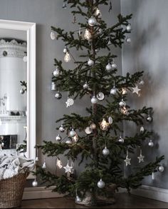 a small christmas tree with silver and white baubles on it's branches